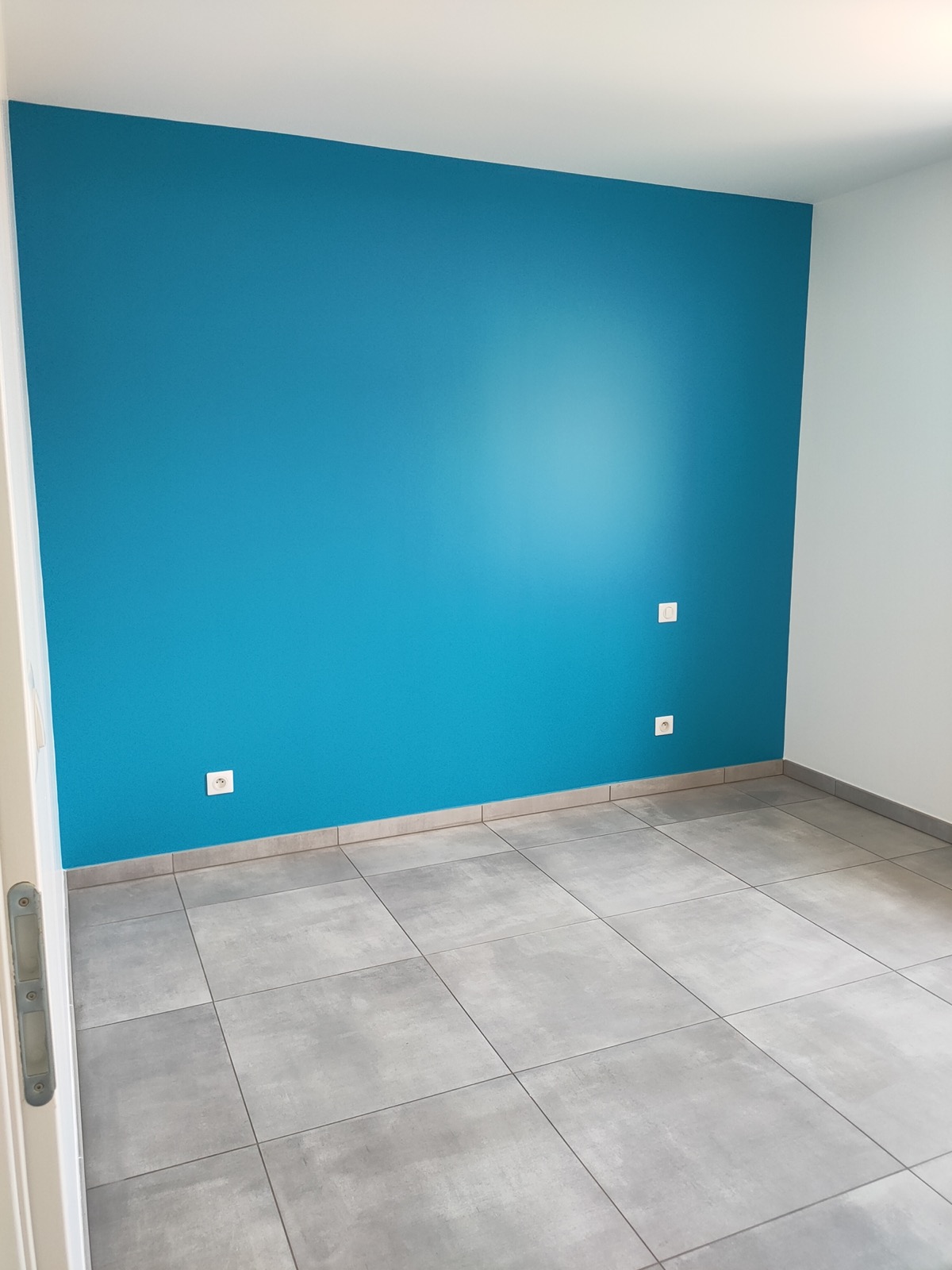Pièce avec un mur peint en bleu turquoise et carrelage gris, par la SARL VIDIEU
